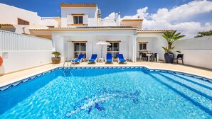 A swimming pool with blue tiles, white walls, and blue lounge chairs.