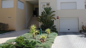A multi-story residential building with a staircase leading to an upper floor. There is a garage door with a 'No Parking' sign, and a small garden area with various plants. - Luxury quiet apartment with private pool near the beach and mountains in Algarve (Portimao)