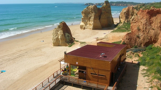 A beach with large rock formations and a wooden building with a red roof. - Luxury quiet apartment with private pool near the beach and mountains in Algarve (Portimao)