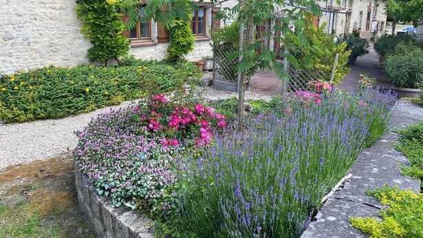 A stone building with a garden featuring various flowers and plants. - Country Cottage / Gite - Poligny (Poligny)