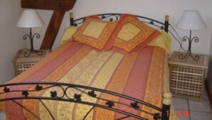 A bed with a striped bedspread and two pillows, flanked by two bedside tables with lamps. - Country Cottage / Gite - Poligny (Poligny)