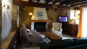 A cozy living room with a stone fireplace, a television, and comfortable seating. - Country Cottage / Gite - Poligny (Poligny)