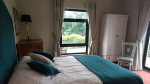A bedroom with a large bed, a window with curtains, a white wardrobe, and a chair. - Family Retreat With Panoramic Lake View And Large Front And Back Gardens (Newmarket-On-Fergus)