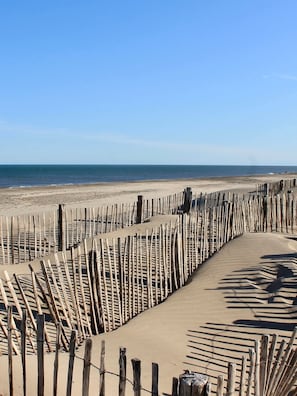 Una playa arenosa con una valla de madera.