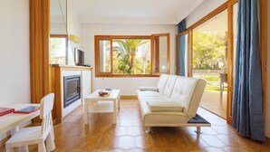 Un salon avec un canapé, une petite table, un téléviseur et une cheminée.