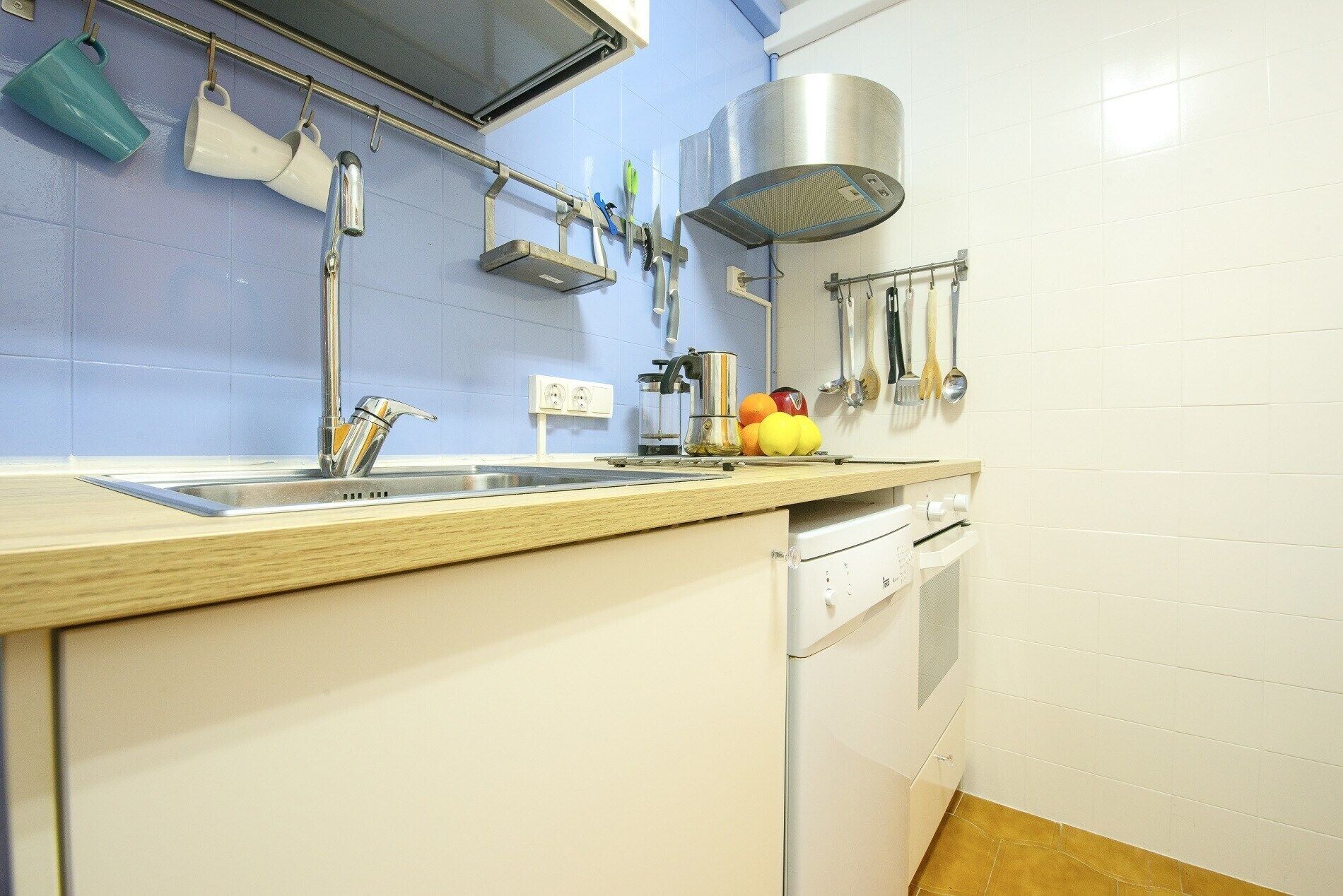 A kitchen with a sink, a stove, and a dish rack.