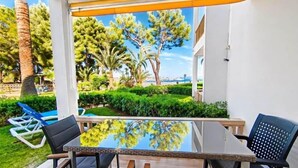 Une terrasse avec une table et des chaises en verre, entourée de verdure et offrant une vue sur des arbres et un bâtiment.