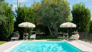 Piscina com dois guarda-sóis e espreguiçadeiras.