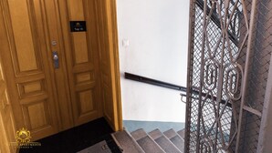 A wooden door with a "Top 16" sign, a metal handrail, and a black doormat.
