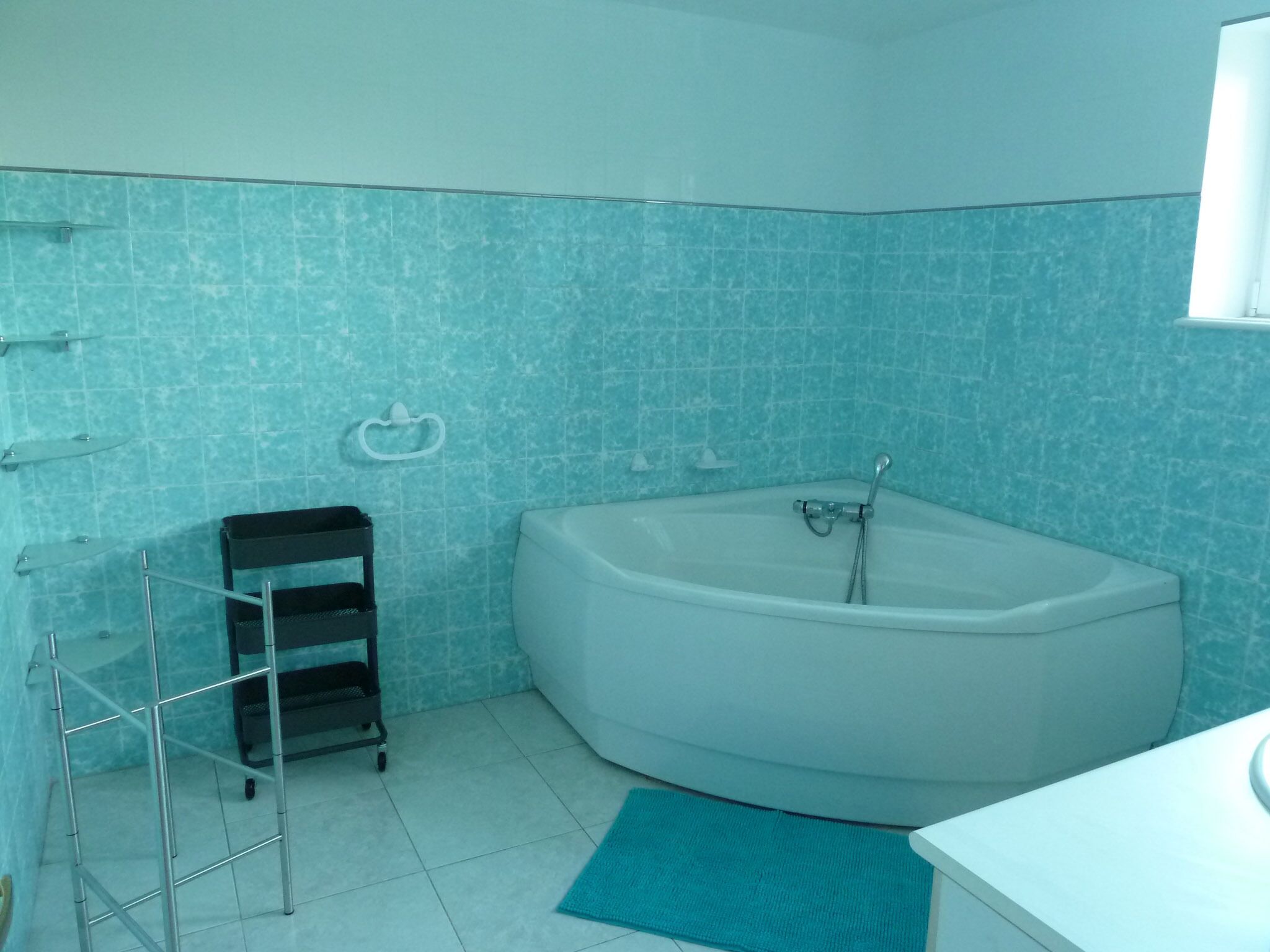 A bathroom with a bathtub, a towel rack, and a metal rack.