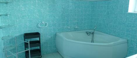 A bathroom with a bathtub, a towel rack, and a metal rack.