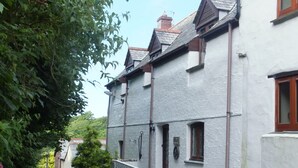 Une rue étroite bordée de bâtiments traditionnels, une voiture garée sur le côté et une végétation luxuriante.
