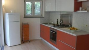 A compact kitchen with a refrigerator, a sink, and a stove. There is a window above the sink and a small cabinet below it. - Apartment/ flat - Monte argentario (Monte Argentario)