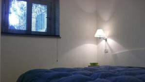A bedroom with a bed, a window with blinds, and a wall-mounted lamp. - Apartment/ flat - Monte argentario (Monte Argentario)