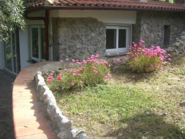 Un edificio de piedra con una ventana y un parterre lleno de flores rosas.