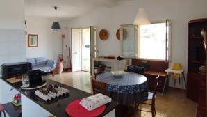 Amplia sala de estar con una mesa de comedor, un sofá y una zona de cocina con microondas.