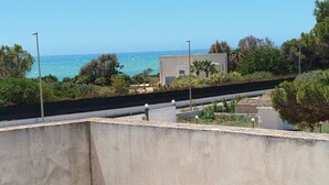 Terraza en la azotea con vistas al mar, un edificio moderno y vegetación circundante.