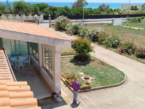 Una propiedad residencial con un patio, mobiliario exterior, un jardín y vista al mar.