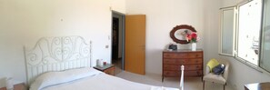 Un dormitorio con cama, cómoda, silla y espejo.