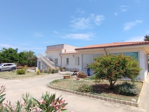 A residential building with a tiled roof, a staircase, and a garden with various plants and flowers.