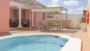 Une piscine agrémentée d’une pergola, d’un espace salon extérieur et offrant une vue sur le ciel.