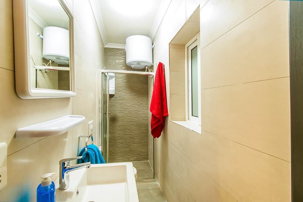 Une petite salle de bain avec une douche, un lavabo et un miroir.