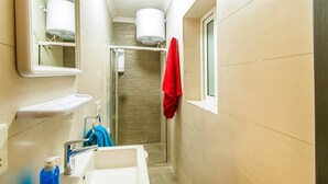 Une petite salle de bain avec une douche, un lavabo et un miroir.