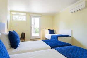 Ein Hotelzimmer mit zwei Betten, einem Fenster, einer Tür und einer Klimaanlage.