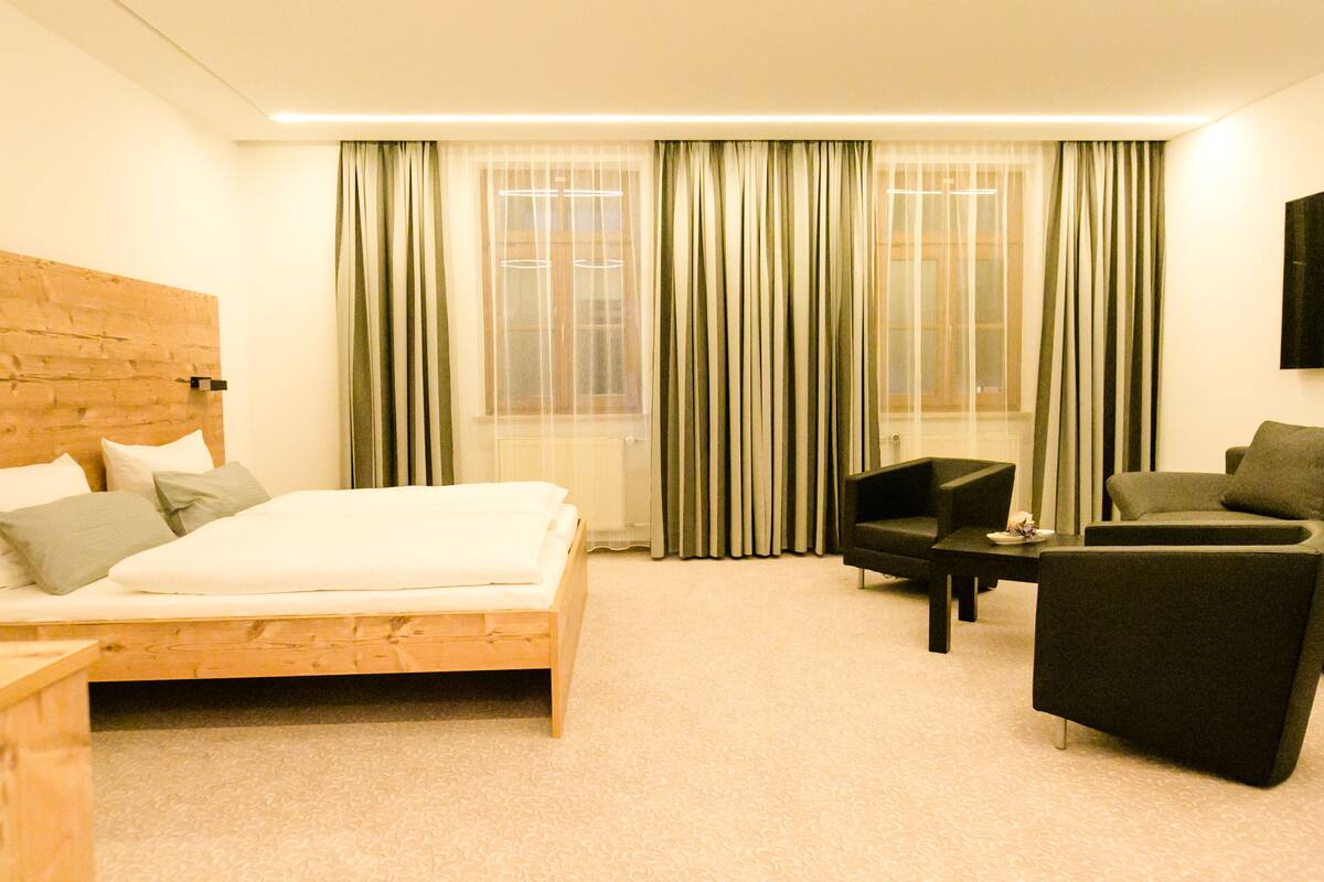 Ein Hotelzimmer mit einem Holzbett, einer Couch, einem kleinen Tisch und einem an der Wand befestigten Fernseher.