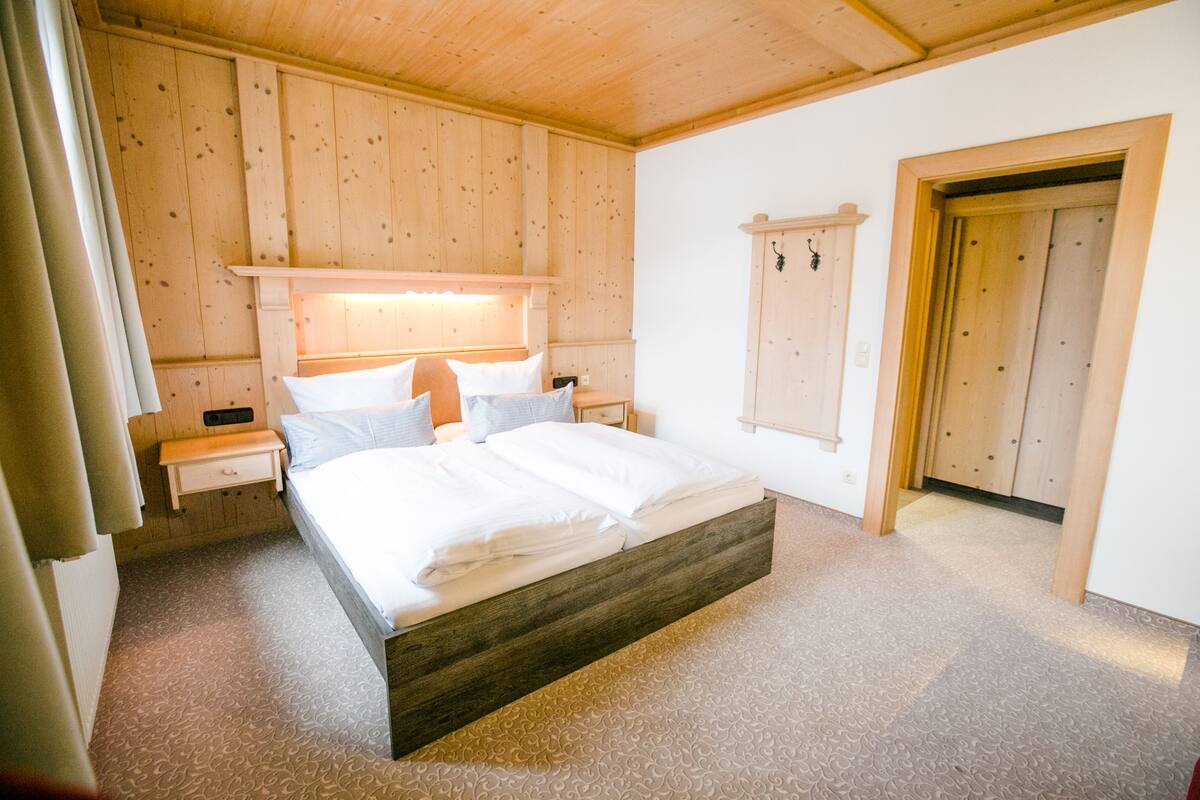 Ein Schlafzimmer mit einem hölzernen Bett, weißer Bettwäsche, einem Nachttisch und einem Holzschrank.