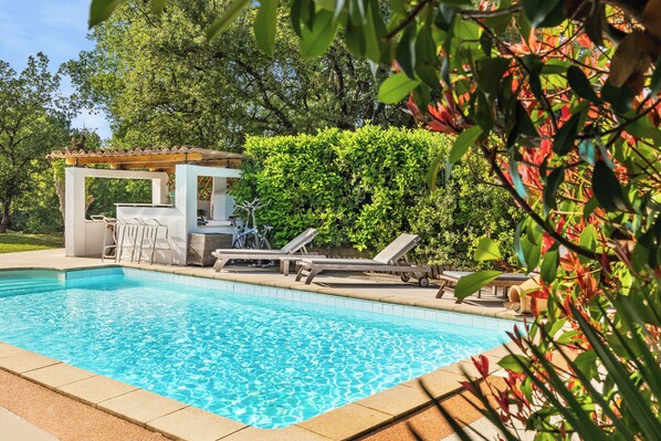 A swimming pool with lounge chairs and a pergola.