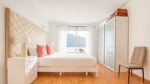 Ein modernes Schlafzimmer mit einem großen Bett, einem Nachttisch, einem Sessel und einem Kleiderschrank.