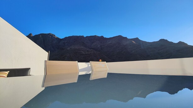 Eine Dachterrasse mit Pool, der Himmel und Berge spiegelt.