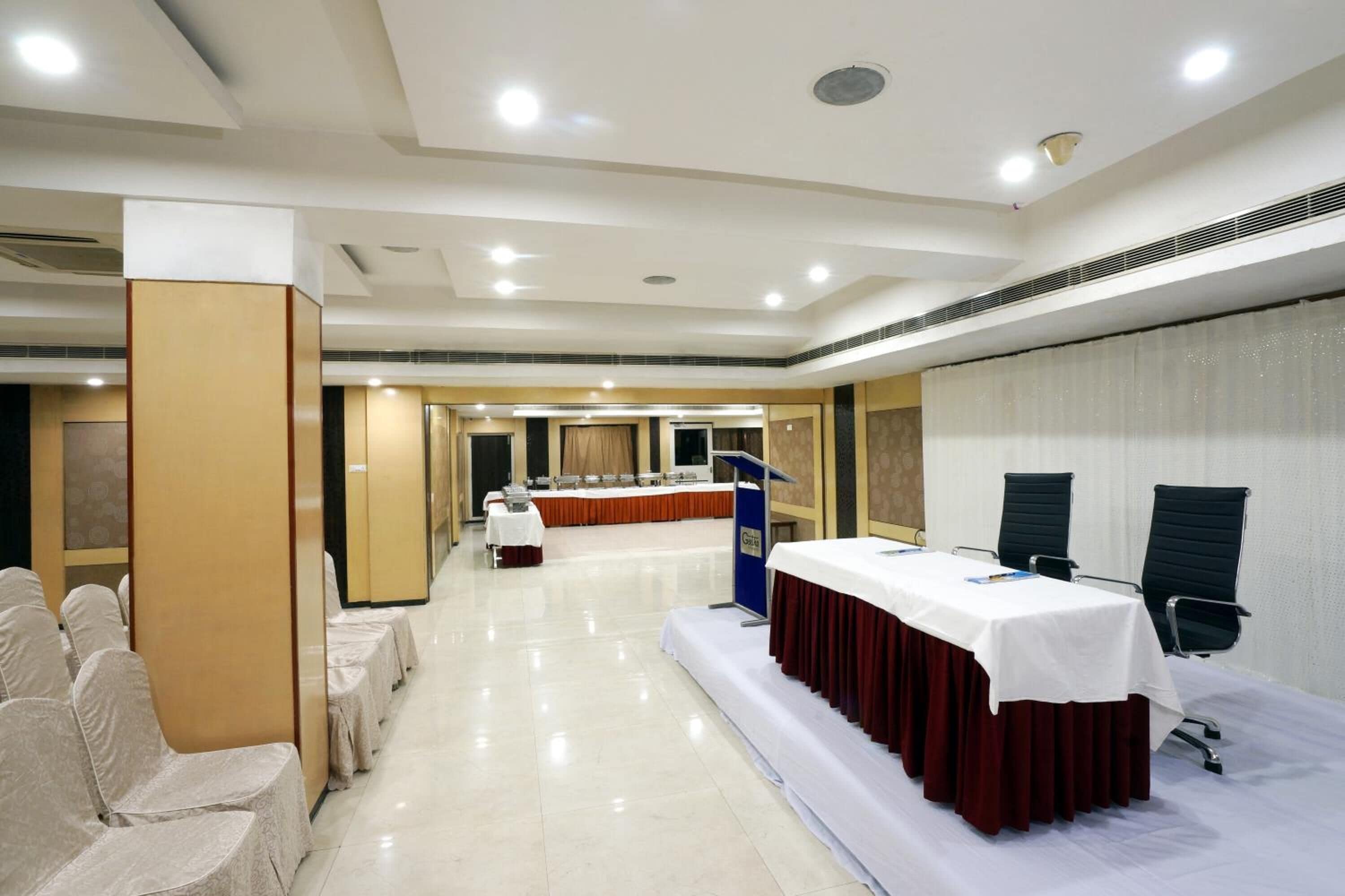A conference room with a stage, a podium, and rows of chairs.