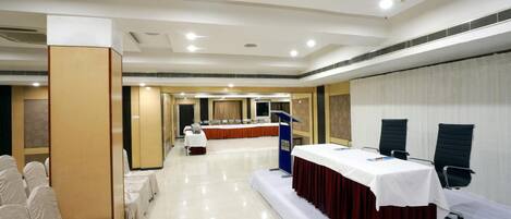 A conference room with a stage, a podium, and rows of chairs.