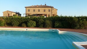 A stone building with a swimming pool in front.