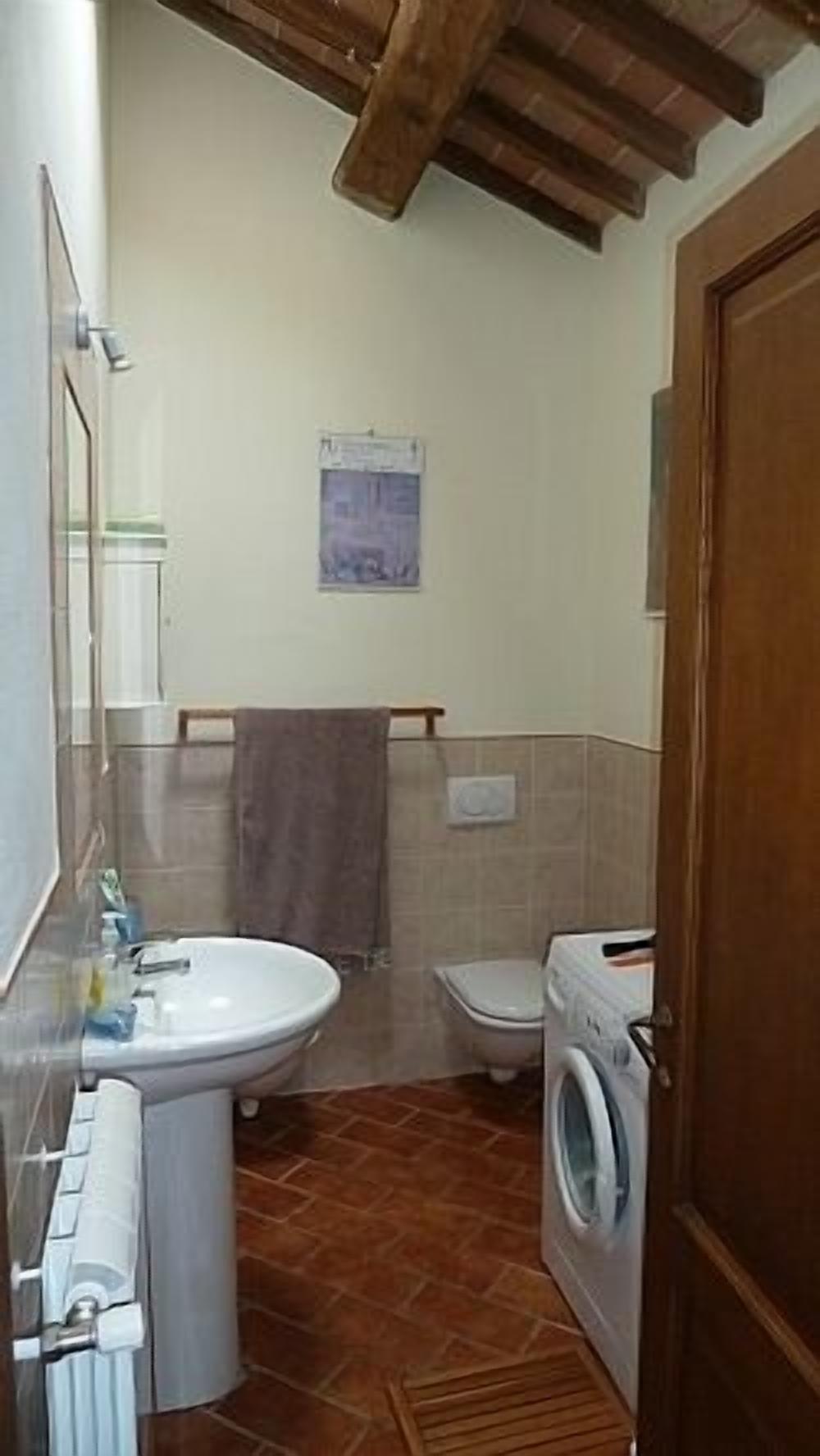 Une petite salle de bain comprenant un lavabo, des toilettes et un lave-linge.