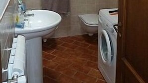 A compact bathroom with a sink, toilet, and washing machine. - Apartment in Beautifully Restored Medieval Tuscan Village, 7klm from Volterra (Pisa)