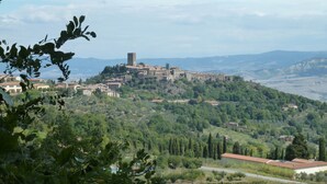 A hillside village with traditional architecture, a prominent tower, and lush greenery. - Apartment in Beautifully Restored Medieval Tuscan Village, 7klm from Volterra (Pisa)