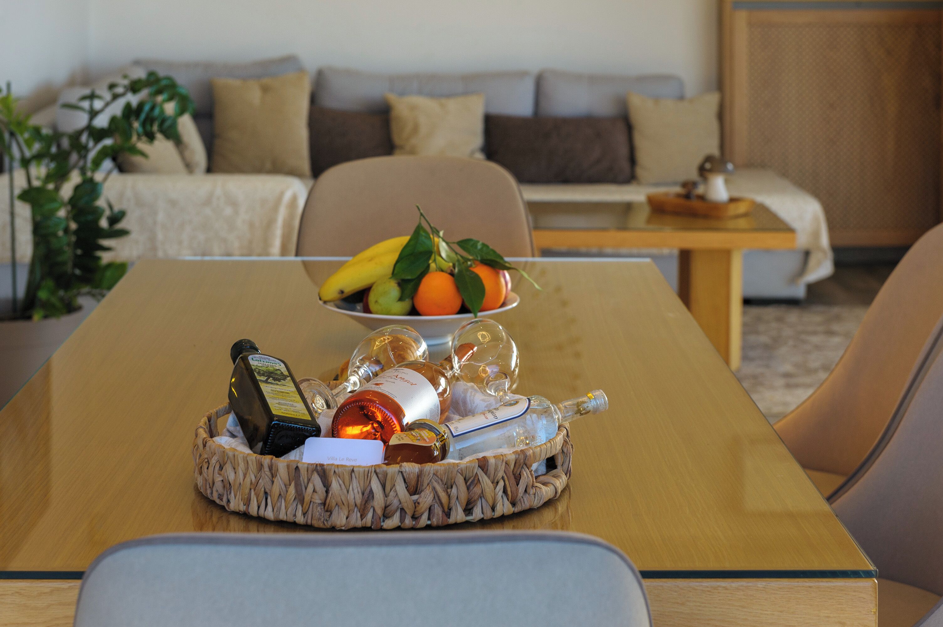 A dining area with a table set with fruits, bottles, and a basket.