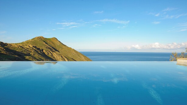 A clear view of an infinity pool with a mountain and ocean in the background. - Perched on a Hill Overlooking the Cretan Sea (Rethymno)