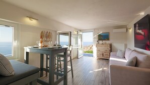 A spacious living area with a dining table, a sofa, and a view of the sea. - Perched on a Hill Overlooking the Cretan Sea (Rethymno)