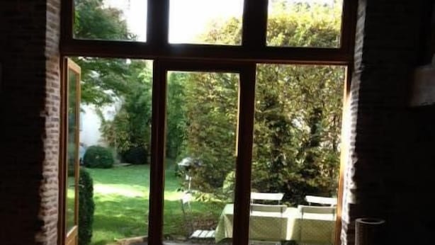 Una habitación con un gran ventanal corredero que da a un jardín.
