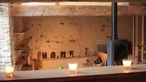 Un interior rústico con paredes de ladrillo visto, una barra de madera y una chimenea a la vista.