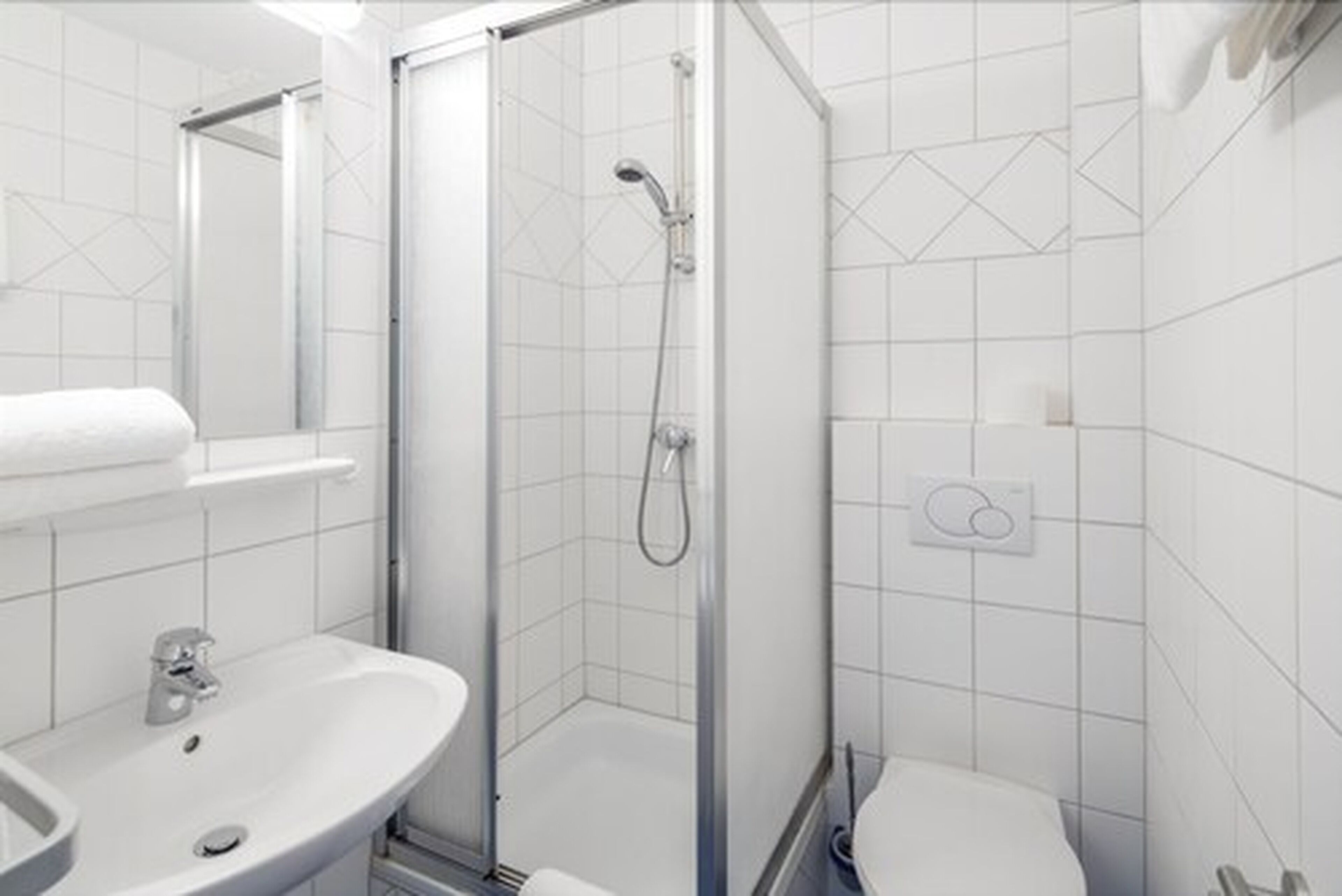 A modern bathroom with a glass-enclosed shower, a sink, and a toilet.