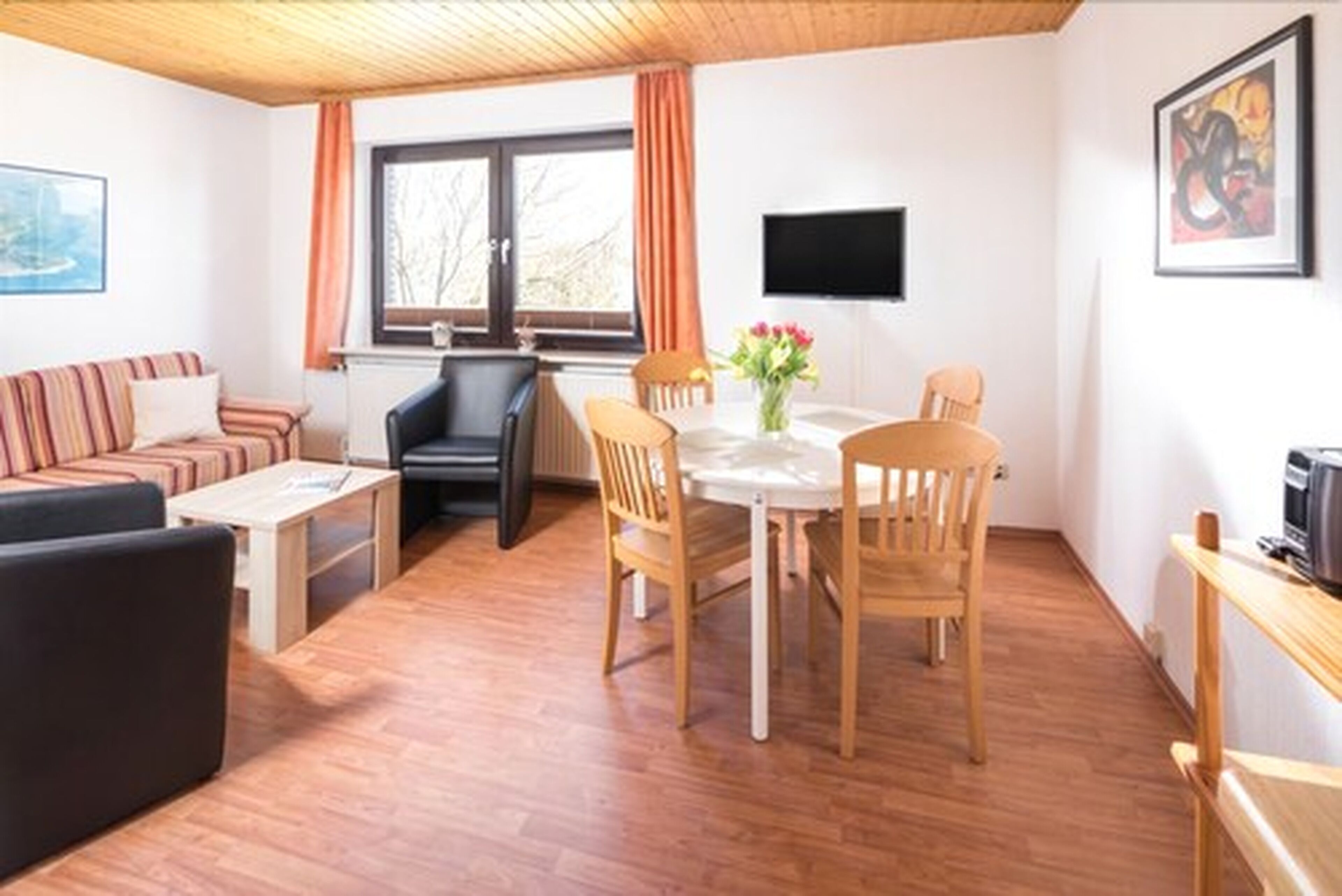 A cozy living room with a sofa, a coffee table, and a dining area with a table and chairs.