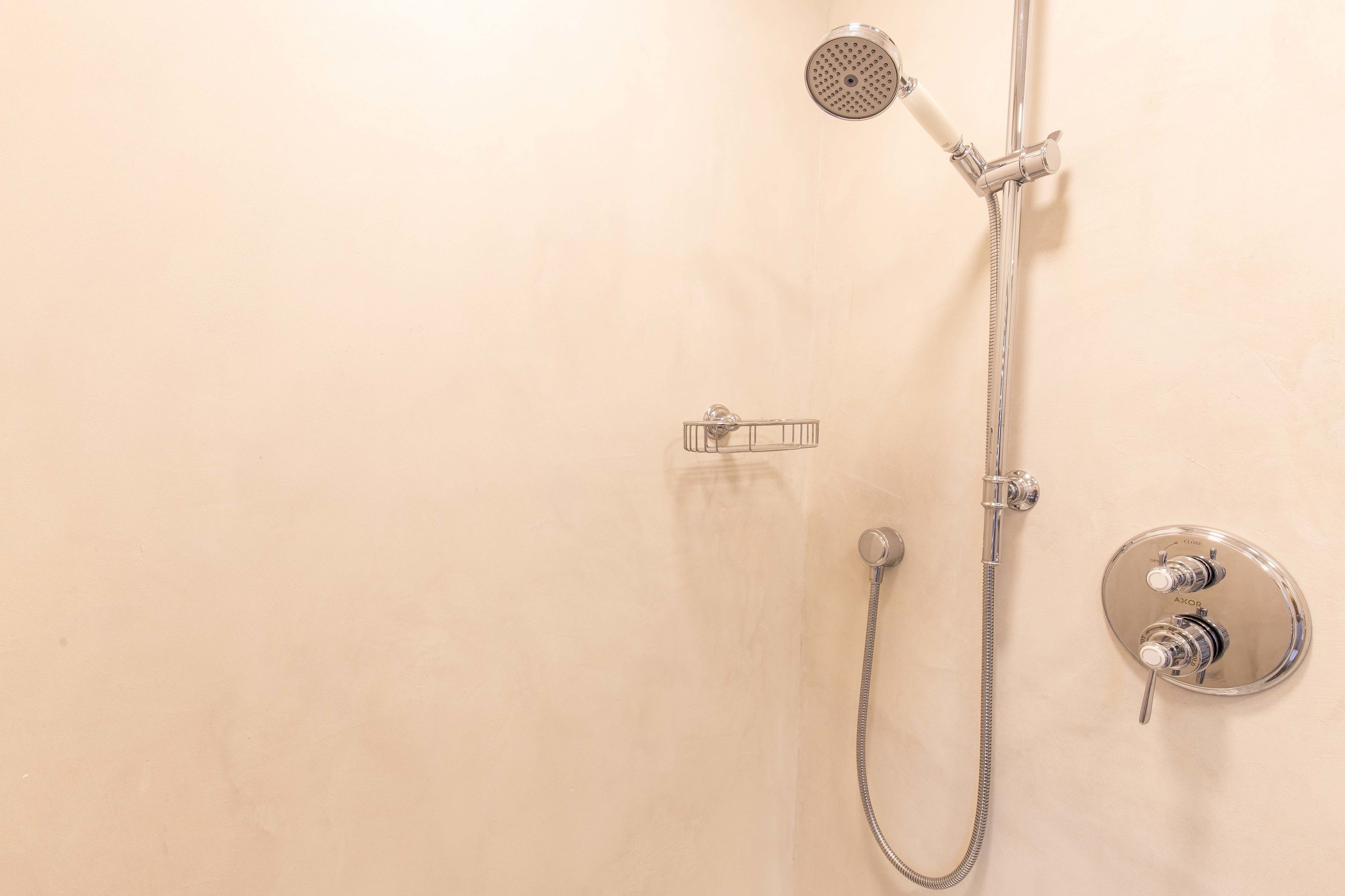 A shower with a handheld showerhead, a handheld shower attachment, and a wall-mounted control valve.