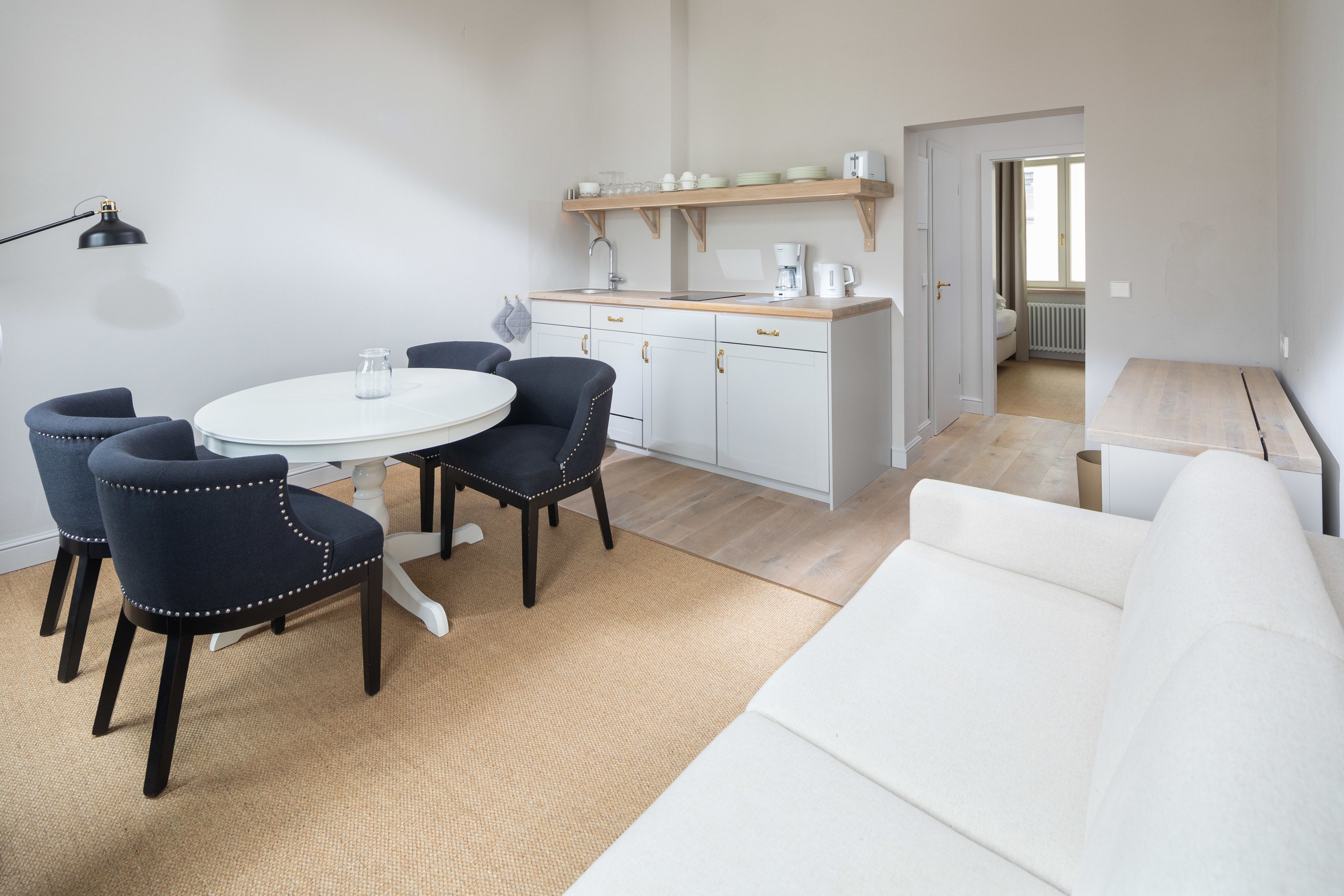 Una cocina moderna con armarios blancos, encimera de madera y un rincón comedor con una mesa redonda y sillas.