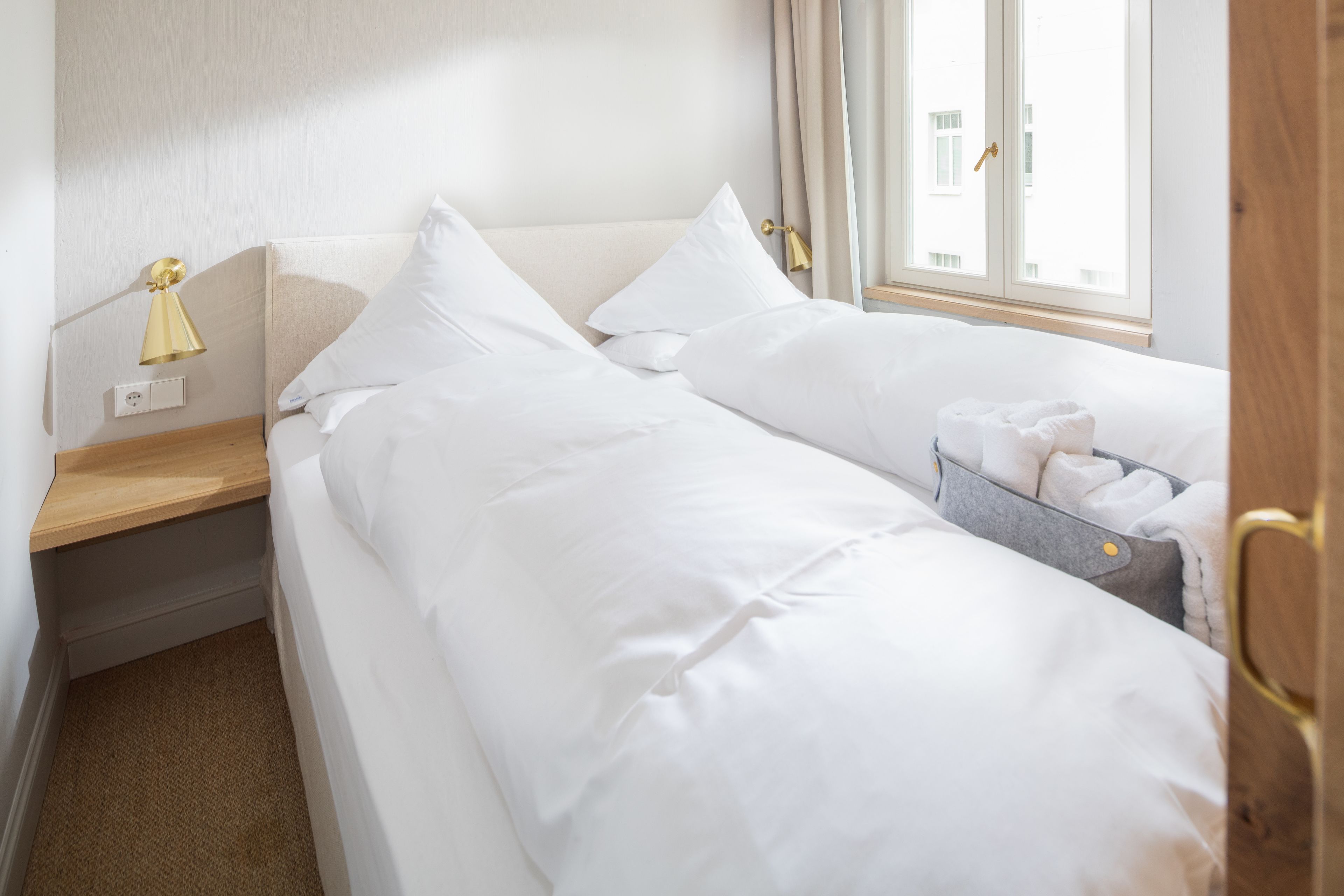 Une chambre d’hôtel avec deux lits, une table de chevet, une lampe et une fenêtre avec des rideaux.
