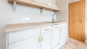 A kitchen with a wooden countertop, white cabinets, and a wooden door.